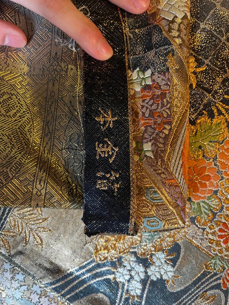 The characters 'hon-kinpaku' woven into the selvage of an obi